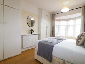 a white bedroom with a large bed and a mirror at 5 Wallace Road in Loughborough