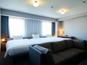 a hotel room with a large bed and a couch at The Knot Utsunomiya in Utsunomiya