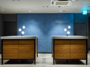 a blue wall with two wooden cabinets in a room at The Knot Utsunomiya in Utsunomiya
