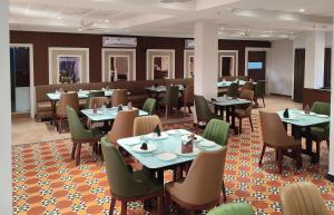 a restaurant with tables and chairs in a room at Hotel Camel managed by CLAY in Mundra