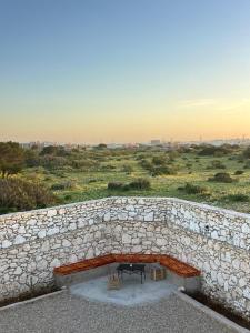 a stone wall with a bench and a table at Turquoise Brick Surf House in Sidi Kaouki