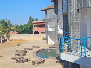a pool with chaise lounges next to a building at Hotel Cap du Sine Saloum in Ndangane