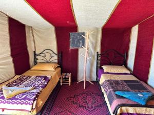 two beds in a room with red and purple walls at Chigaga Luxury Camp in Mhamid
