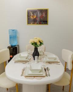 a white table with plates and a vase of flowers at Riara One Residency in Gatunga +10 photos