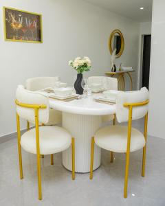 a white table with chairs and a white table with flowers at Riara One Residency in Gatunga