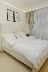 a bedroom with a white bed with white sheets at Riara One Residency in Gatunga
