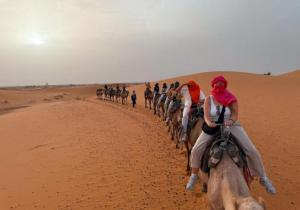 a group of people riding horses in the desert at Merzouga Dream Camp in Merzouga