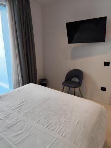 a bedroom with a bed and a chair and a television at Gabbiano Suites in Cervia