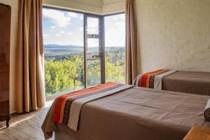 two beds in a room with a large window at Phillipskop Eco-Chalets in Stanford