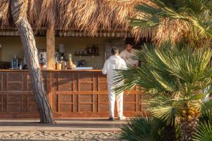 two people standing at a bar at a resort at NOMAD ARGENTARIO - Area Sosta Camper - NO TENDE - NO CARAVAN - Empty Pitch Only Campervan RV - SOLO PIAZZOLA PER IL PROPRIO CAMPER - Tariffa fino a 4 persone - TUTTI I SERVIZI INCLUSI in Albinia