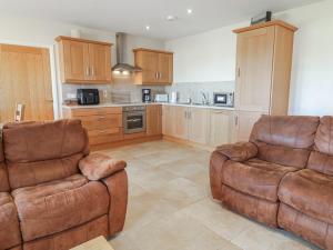 a kitchen with two leather chairs and a couch at Finn Cottage in Strabane