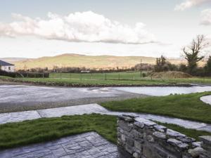 a stone wall next to a road with a pond at Finn Cottage in Strabane