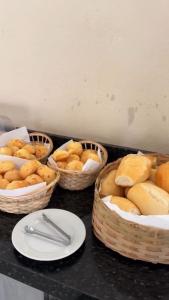 four baskets of food on a counter with plates and silverware at Pousada Casa de Naná in Palmas