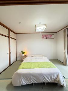 a bedroom with a large bed with a green blanket at 禅 宮島 一棟貸し 最大6名 ダブルベット3台 2階建の1棟貸しホテル in Hatsukaichi
