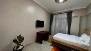a bedroom with a bed and a tv on the wall at Kuri hotel Kampala in Kampala