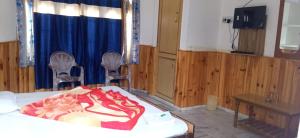 a room with a bed and two chairs and a table at Hotel Kailash View, Kalpa in Kalpa
