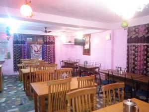 a restaurant with wooden tables and chairs and pink walls at Hotel Kailash View, Kalpa in Kalpa