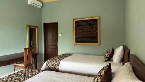 a bedroom with two beds and a picture on the wall at Shima Tunjung in Darmasaba