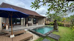 a house with a swimming pool and an umbrella at Shima Tunjung in Darmasaba