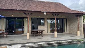 a house with a table and chairs next to a pool at Shima Tunjung in Darmasaba