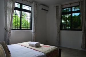 a bedroom with two windows and a bed with towels on it at Airways Residence in Plaine Magnien