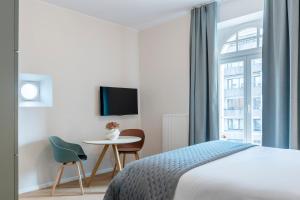 a bedroom with a bed and a table and a window at Key Inn serviced residences Belair in Luxembourg