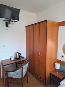 a bedroom with a wooden cabinet and a desk with a table at Penzion Borlitz in Pohořelice