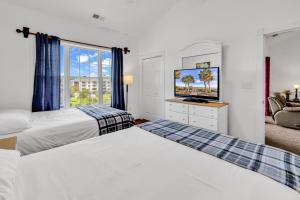 a bedroom with two beds and a tv and a window at Myrtlewood by Monarch Rentals in Myrtle Beach