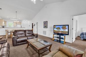 a living room with leather furniture and a flat screen tv at Myrtlewood by Monarch Rentals in Myrtle Beach