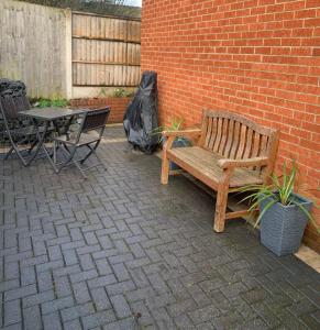 a wooden bench sitting next to a brick wall with a table at The Coach House, Cleobury Mortimer in Cleobury Mortimer