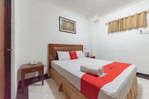 a bedroom with a large bed with a red blanket at RedDoorz Plus at Buah Batu in Bandung