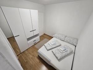 a small white room with a bed and a cabinet at Airport Apartment in Surčin
