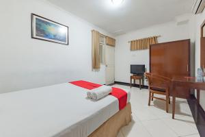a bedroom with a bed and a desk in a room at RedDoorz Plus at Buah Batu in Bandung