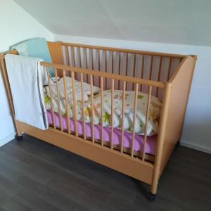 a wooden crib with a blanket on it at Farbenfrohe Dachgeschoßwohnung in Giesen