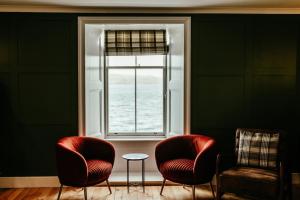 two chairs and a table in front of a window at The Seadoor, Shetland Islands in Lerwick