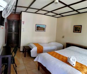 a hotel room with two beds and a table at Hotel Wagelia Turrialba in Turrialba +40 photos