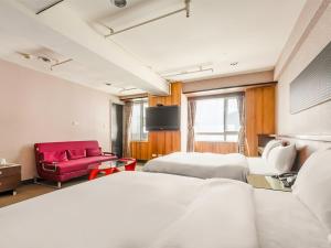 a hotel room with two beds and a red couch at CHECK inn Express Taichung Fengchia in Taichung