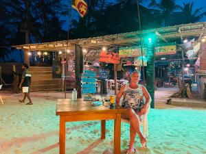 a man sitting at a table on the beach at Beach Lovers Tiny House in Nilaveli