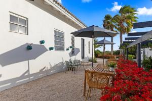 a patio with a table and an umbrella and flowers at Saint Joris a tiny Boutique Resort in Willemstad