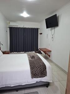 a bedroom with a white bed and a television at Unit 17 Sunbird Self-Catering in Richards Bay