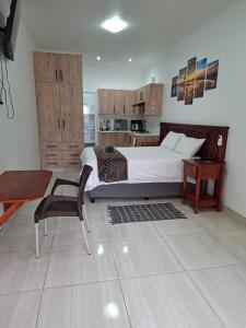 a bedroom with a bed and a table and a chair at Unit 17 Sunbird Self-Catering in Richards Bay