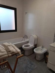 a bathroom with a toilet and a tub and a sink at Sunny Sunset House in Ponta do Pargo