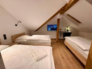 a attic room with two beds and a television at Vila Vladorena in Požega