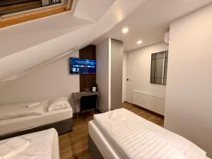 a hotel room with two beds and a tv at Vila Vladorena in Požega