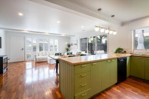 a kitchen with green cabinets and a living room at Fireplace & Winter Swells, 800m to the beach in Ocean Grove