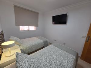a small room with two beds and a television at Estrella y mar in La Estrella