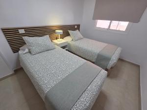 a bedroom with two beds and a table with a lamp at Estrella y mar in La Estrella
