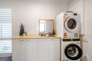a kitchen with a washing machine and a sink at Fireplace & Winter Swells, 800m to the beach in Ocean Grove