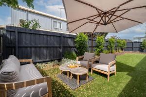 a patio with an umbrella and chairs and a table at Fireplace & Winter Swells, 800m to the beach in Ocean Grove