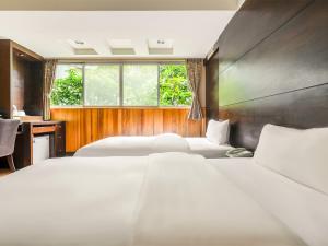 a bedroom with three beds and a window at CHECK inn Express Taichung Fengchia in Taichung +82 photos